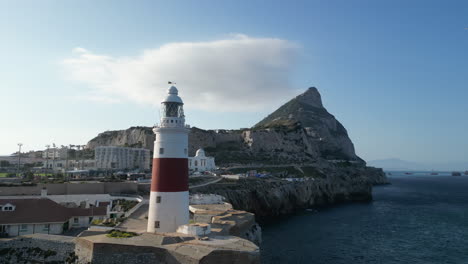 Eine-Malerische-4K-Drohnenaufnahme,-Die-Aus-Dem-Meer-Aufsteigt-Und-Einen-Leuchtturm-Und-Den-Felsen-Von-Gibraltar-An-Seinem-Südlichsten-Punkt-Enthüllt