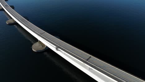 Closeup-aerial-view-of-a-lane-on-Nordhordland-Bridge,-capturing-a-bus-passing-over-the-floating-structure