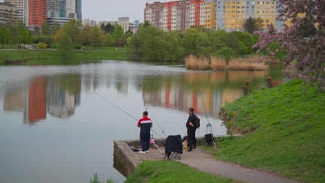 Fisherman-use-fishing-rod-at-Nepomuk-pond,-Central-park-Prague,-city-background