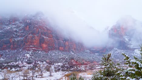 Wide-shot-of-the-snowy,-cloud-covered-mountains-of-Zion-National-Park-with-a-river-below