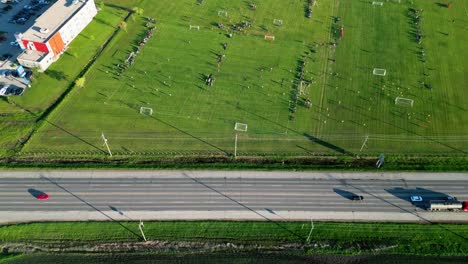 Autos-Fahren-Auf-Einer-Großen-Autobahn,-Während-Kinder-Im-Sommer-In-Winnipeg,-Manitoba,-Kanada-Auf-Einer-Reihe-Von-Outdoor-Fußballfeldern-Spielen