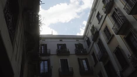 A-neighborhood-of-Barcelona,-Spain,-with-bright-clouds-and-birds-in-a-low-angle-shot