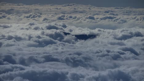 Großer-Zeitraffer-Aus-Der-Luft-Von-Flauschigen-Wolken,-Die-An-Einem-Dunklen-Berggipfel-Vorbeiziehen