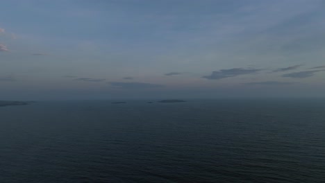 Evening-aerial-at-dawn,-approaching-island-with-Marsteinen-lighthouse-in-the-distant,-north-sea-background