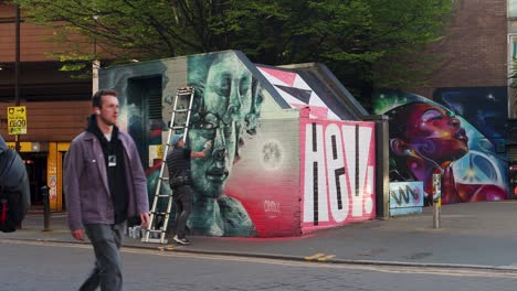 Street-artist-paints-mural-while-people-walk-by-in-Manchester's-Northern-Quarter