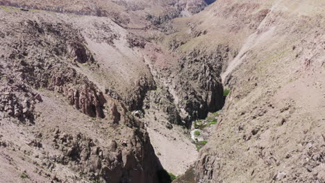 Luftaufnahmen-Fangen-Eine-Dramatische-Wüstenlandschaft-Mit-Steilen-Klippen,-Schroffen-Felsen-Und-Einem-Gewundenen-Tal-Ein