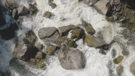 Rushing-water-over-large-rocks-in-owen-sound,-canada-creating-a-dramatic-natural-scene,-aerial-view