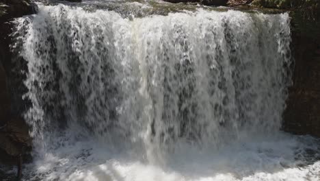 Small-waterfall-cascading-over-rocky-ledge-in-Owen-Sound,-Canada-with-lush-greenery-around