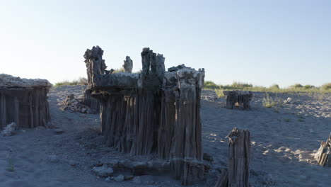 Aerial-shot-of-Mono-Lake's-tufa-towers-with-surrounding-desert-and-mountain-landscape-under-a-bright,-sunny-sky,-capturing-the-serene-and-expansive-environment