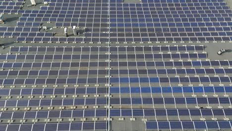 Drone-shot-of-the-solar-panels-on-a-production-building-roof-on-a-sunny-day