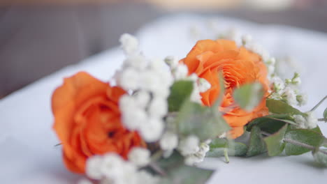 Orange-Und-Weiß-Floral-Boutonniere-Ist-Auf-Einem-Tisch