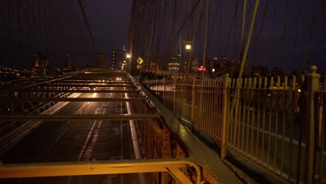 Cinematic-Brooklyn-Bridge-Deck-Cars-Passing-Below-Pan-Right-To-People-Walking