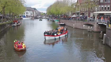 Menschen-Feiern-Den-Königstag-Auf-Einem-Boot-In-Einem-Utrechter-Kanal,-Umgeben-Von-Festlichen-Menschenmengen-Und-Historischen-Gebäuden