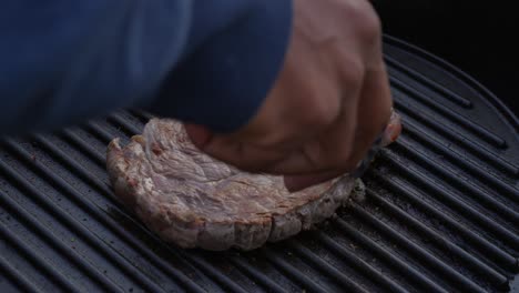 Close-up-of-juicy-beef-steak-flipped-around-with-tongs-on-hot-grill