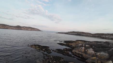 FPV-aerial-cruising-at-low-altitude-around-coastal-islands-near-Sotra-and-Bergen,-Norway,-close-to-the-sea-surface-at-sunset