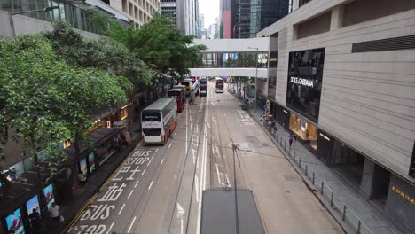 Mit-Blick-Auf-Die-Des-Voeux-Road-Central-Mit-Doppeldeckerbussen,-Die-Neben-Hochwertigen-Bekleidungsgeschäften-Vorbeifahren