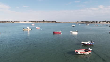 Low-drone-flight-over-bay-in-Guernsey-with-boats-at-anchor-crystal-clear-water-and-golden-beaches-on-bright-sunny-calm-day