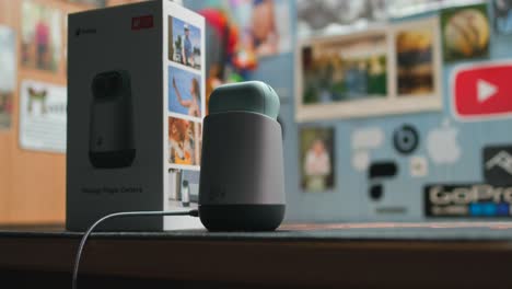 A-home-video-security-camera-rotates-on-its-base-on-desk-next-to-product-box