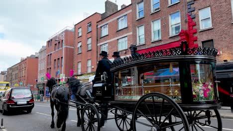 Eine-4k-Aufnahme-Eines-Schwarzen-Leichenwagens,-Der-Von-Schwarzen-Pferden-Gezogen-Wird,-Auf-Einer-Straße-In-Dublin,-Irland