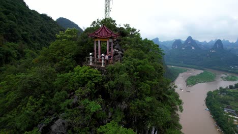 Aerial-parallax-shot-of-a-couple-at-a-pagoda-on-Laozhai-Hill-in-Xingping-Ancient-Town,-China