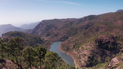 Drone-Aéreo-Volando-Sobre-La-Línea-De-árboles-Alrededor-De-Un-Embalse-De-Lago-En-Las-Montañas-De-Gran-Canaria-España