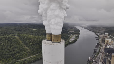 Brilliant-Ohio-Aerial-v6-drone-fly-around-power-utility-plant-capturing-flue-gas-stack's-emitting-white-smoke-plume-against-hillside-town-and-river---Shot-with-Mavic-3-Pro-Cine---September-2023