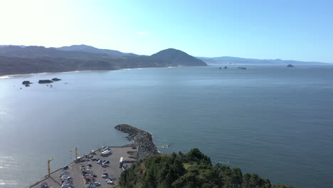 Drone-flying-over-hill-in-Port-Orford-Oregon,-revealing-dry-dock-harbor