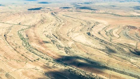 Aerial-view-of-the-dry-Australian-outback-landscape,-with-vast-desert-plains-and-cloud-shadows