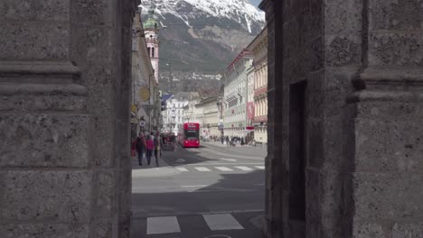 A-tram-driving-down-Maria-Theresien-Street,-viewed-through-one-of-the-arches-of-the-Triumphal-Arch,-Innsbruck,-Tirol,-Austria