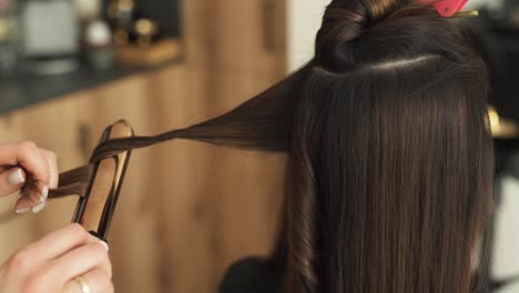 Primer-Plano-De-Las-Manos-De-Un-Peluquero-Rizando-El-Cabello-Con-Un-Rizador-Para-Darle-Volumen-En-Un-Salón-De-Belleza-Y-Bienestar