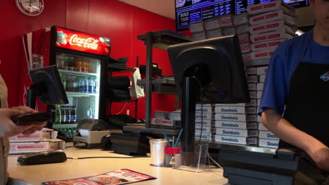 Customer-buying-Domino-pizza-and-taking-receipt-at-check-out-counter-with-4k-resolution