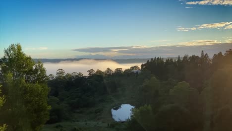 Breath-taking-dawn-sunrise-in-the-Sunshine-Coast-Hinterland-at-Maleny,-Queensland-with-fog-flowing-and-boiling-through-the-valley-as-the-sun-comes-up-illuminating-the-drifting-fog