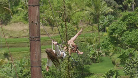 Una-Joven-Vestida-De-Blanco-Se-Balancea-Juguetonamente-En-Los-Pintorescos-Campos-De-Arroz-De-Tegalalang,-Bali,-Indonesia.