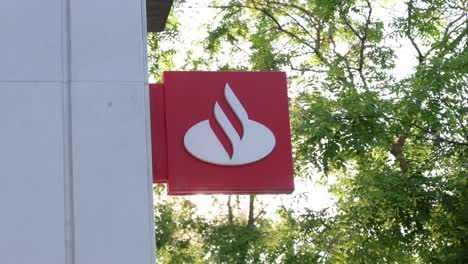 A-company-logo-sign-from-the-Spanish-multinational-commercial-bank-and-financial-services-enterprise,-Santander-bank,-is-seen-outside-a-branch-in-Spain