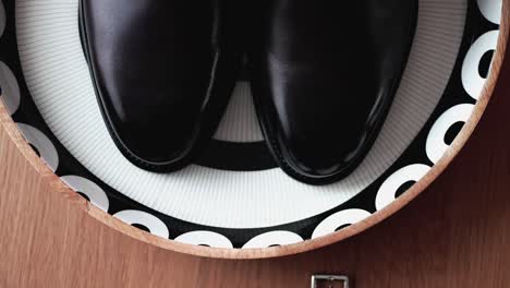 Close-up-of-polished-black-wedding-shoes-on-a-decorative-plate,-showcasing-elegance-and-style