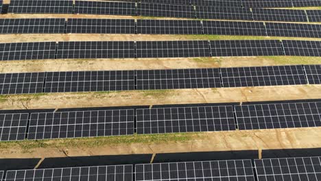 Aerial-shot-of-large-power-plant-of-solar-panels-in-Electrum-solar-park-in-a-vast-field-on-a-sunny-day-in-Taurage,-Lithuania,-zooming-out