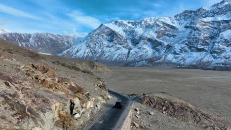 Vista-Aérea-Trasera-De-Un-Vehículo-Que-Circula-Por-El-Valle-De-Skardu-En-El-Frío-Desierto-De-Sarfaranga-En-Pakistán.