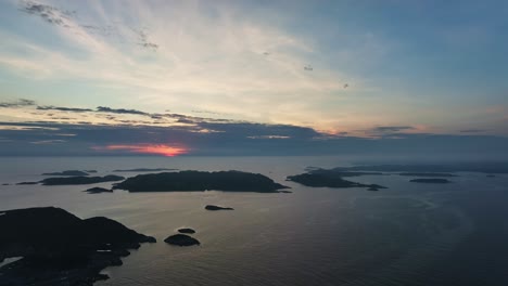 Drone-moves-sideways-over-small-coastal-islands-in-the-North-Sea-with-a-vibrant-sunset-in-the-background