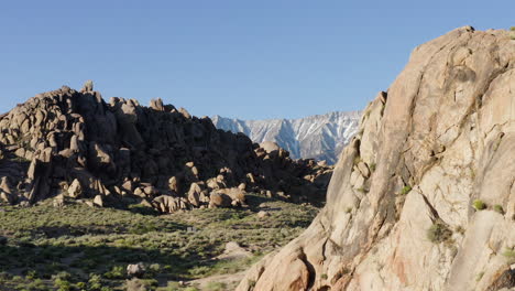 Epic-aerial-shot-of-Alabama-Hills'-rock-formations-with-Owens-River-Gorge-in-the-background,-showcasing-the-dramatic-and-rugged-terrain