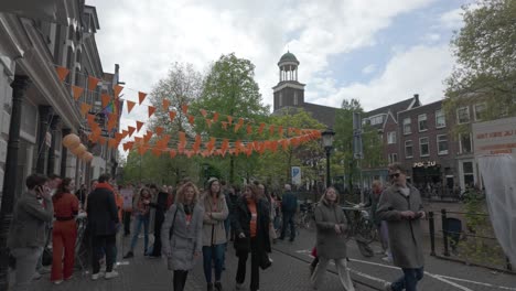 People-celebrating-King's-Day-in-Utrecht,-Netherlands-under-orange-bunting