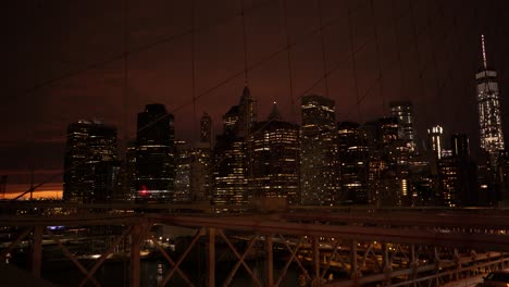 Puesta-De-Sol-Del-Puente-De-Brooklyn-Y-Autos-Del-Bajo-Manhattan-Pasando-Debajo-De-La-Torre-De-La-Libertad