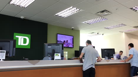 People-at-a-bank-counter-talking-to-the-teller-inside-TD-Bank-with-4k-resolution