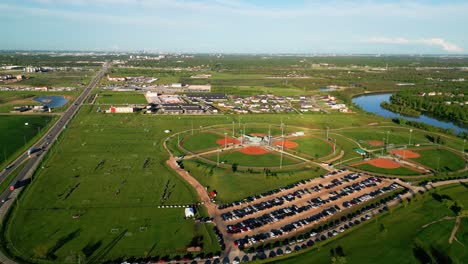 Drohnenumlaufbahn-über-Einem-Sportkomplex.-Menschen-Spielen-Auf-Einem-Fußballplatz-Im-Freien-In-Einem-Park-Auf-Dem-Land-Mit-Winnipeg,-Manitoba-Im-Hintergrund