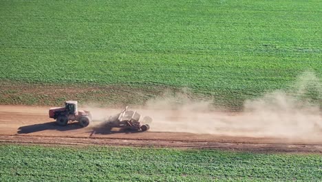 Tractor-with-small-grader-at-speed-along-a-dirt-road-and-bringing-up-plenty-of-dust