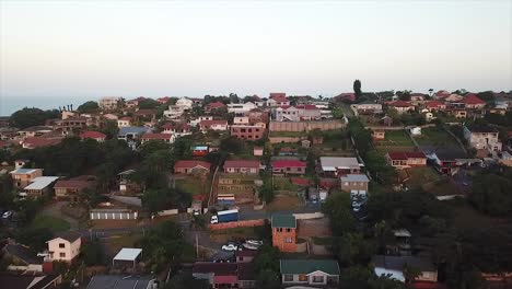 Drone-Volando-Sobre-Algunas-Coloridas-Casas-Residenciales-Con-Una-Ligera-Vista-Al-Mar-En-La-Distancia-En-El-Acantilado-En-Durban,-Sudáfrica