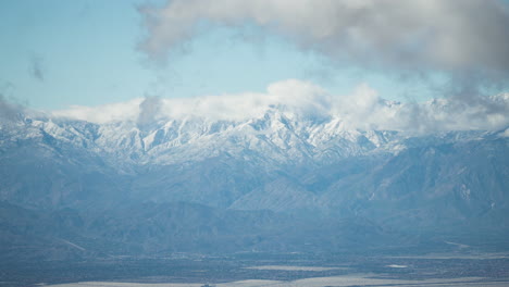 A-breathtaking-panorama-showcases-Joshua-Tree-dusted-with-snow,-captured-by-a-drone-at-dawn-with-slow-moving-clouds