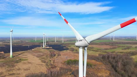 drone-footage-of-wind-turbines-in-a-wind-farm-generating-green-electric-energy-on-a-wide-green-field-on-a-sunny-day,-in-Taurage,-Lithuania