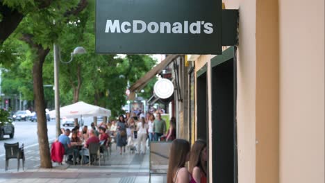 A-sign-from-the-American-multinational-fast-food-hamburger-restaurant-chain,-McDonald's,-as-customers-enter-the-branch-in-Madrid,-Spain