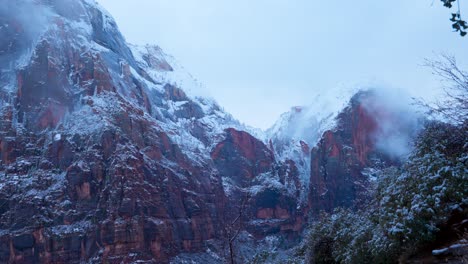 Una-Montaña-Cubierta-De-Nieve-En-Un-Día-Frío-En-El-Parque-Nacional-Zion-Mientras-El-Sol-Se-Pone-Y-Las-Nubes-Cubren-Los-Picos