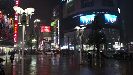 Typhoon-passing-over-Tokyo,-people-walking-through-Shinjuku-at-night